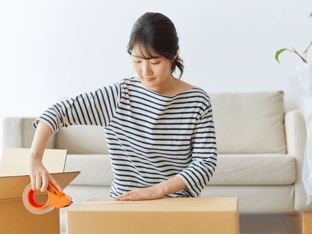 a woman packs decluttered items into a box to be placed in a storage unit.