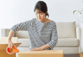 a woman packs decluttered items into a box to be placed in a storage unit.